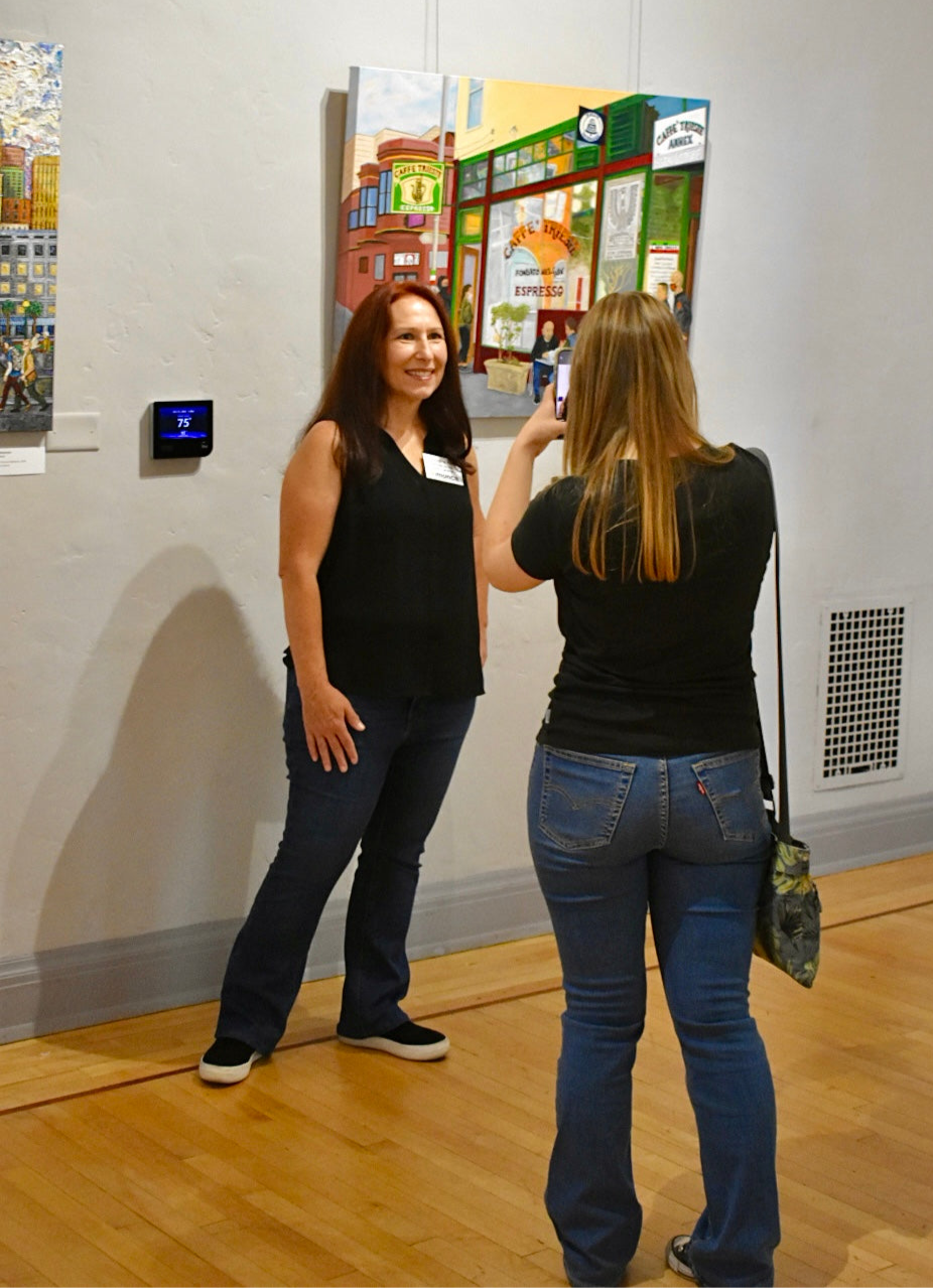 Two women looking at artwork in a gallery setting.