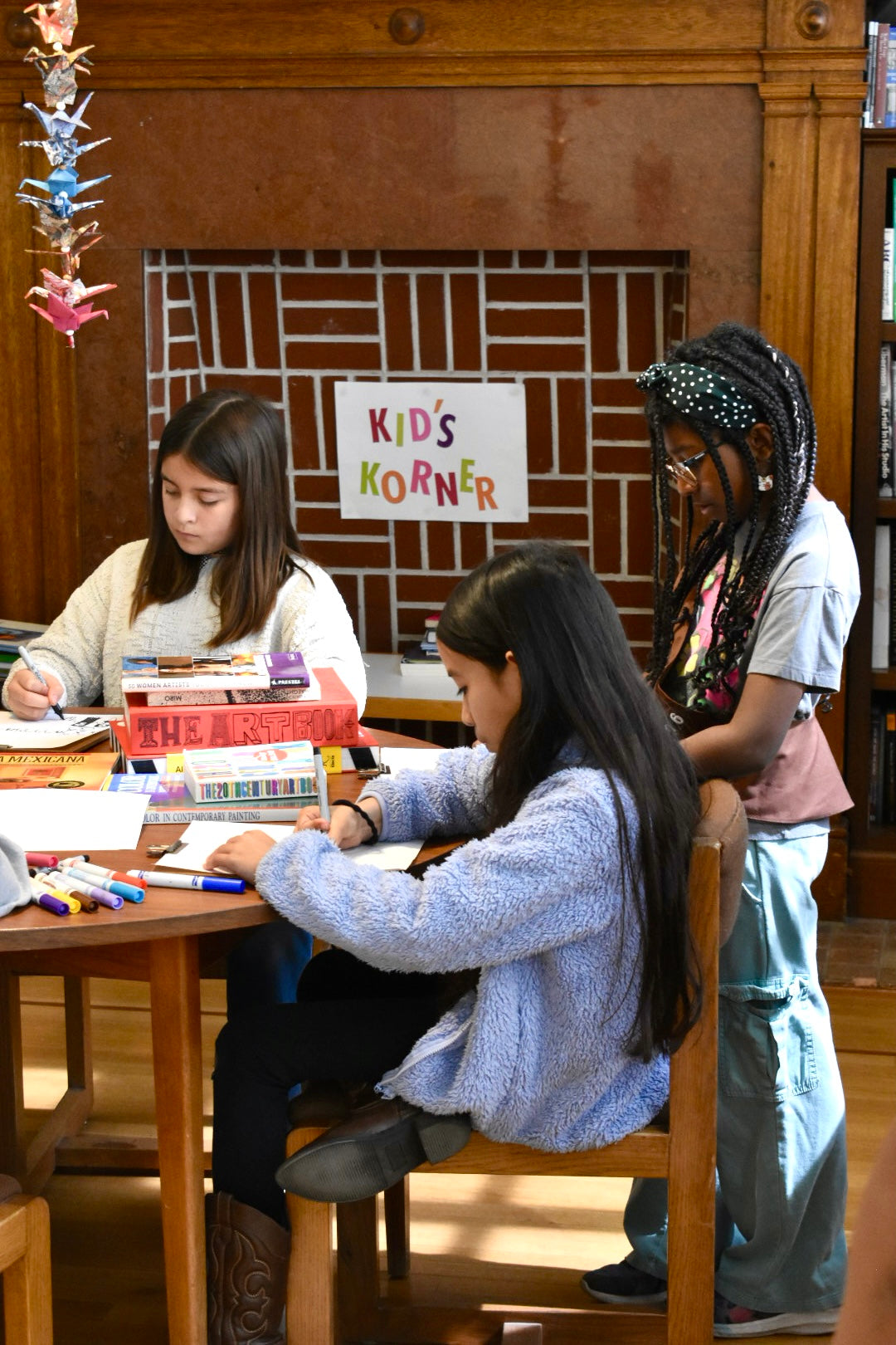 Children in a library setting with a 'Kids' Corner' sign in the background.
