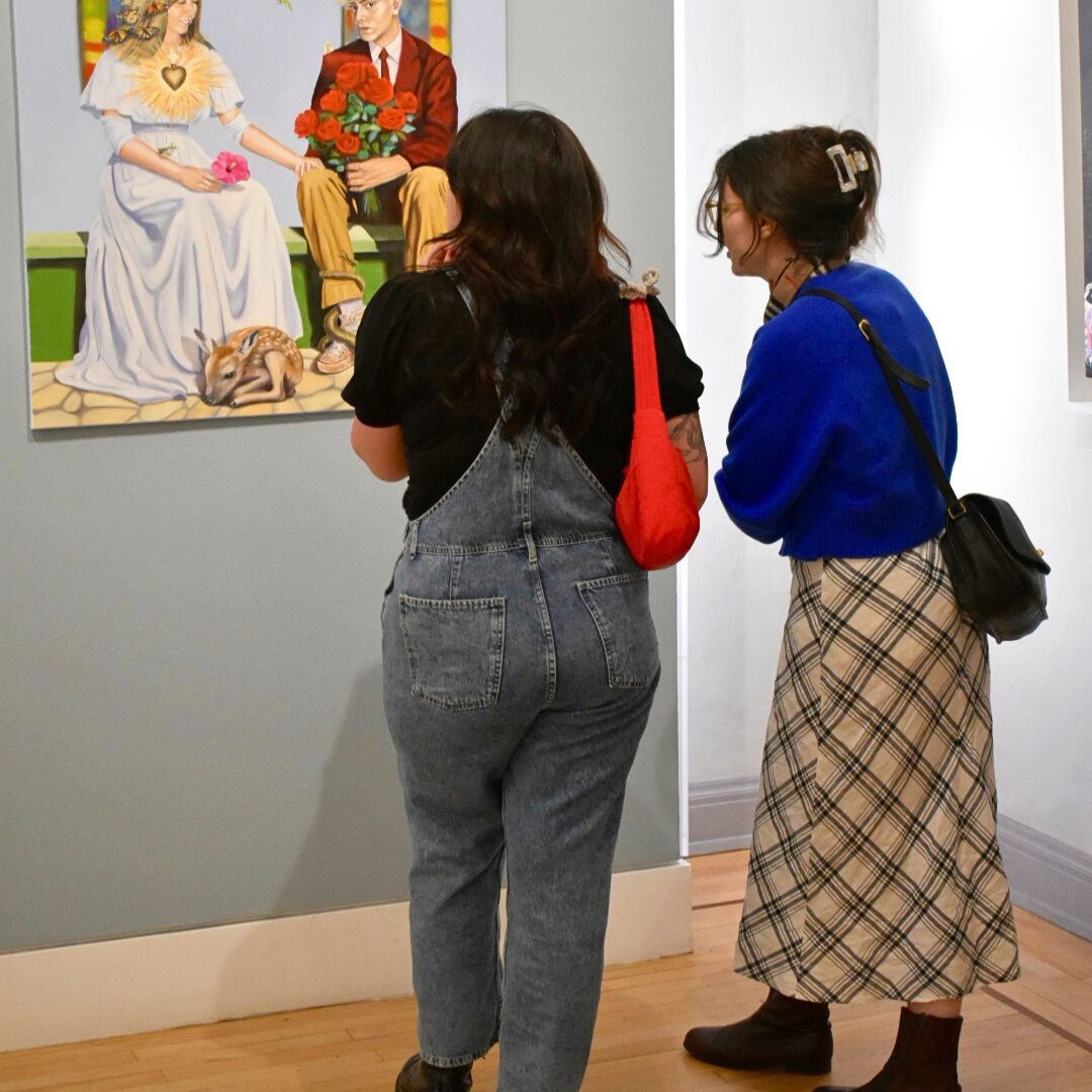 Two people observing a painting in an art gallery.