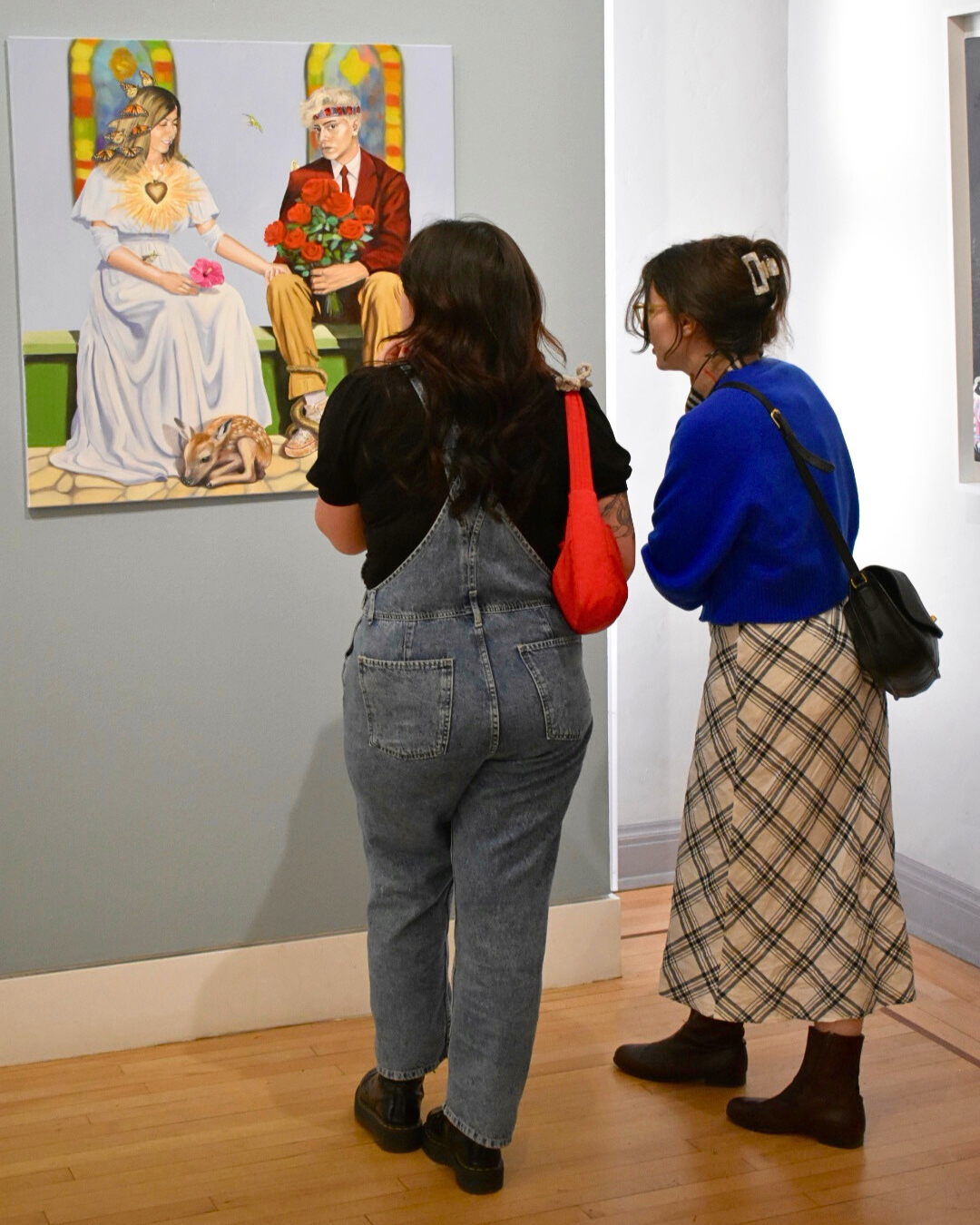 Two people observing a painting in an art gallery.