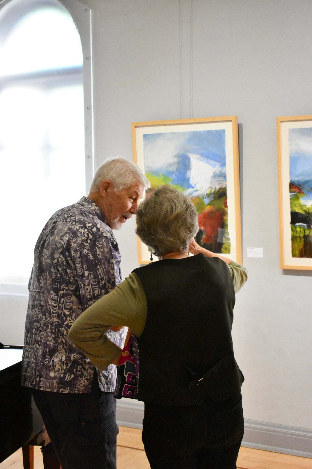 Two people looking at a painting in an art gallery.