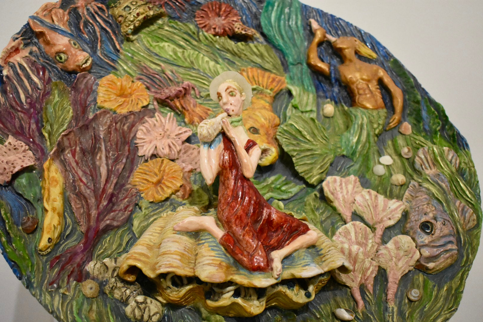 Decorative wall piece with a figurine of a woman in a red dress sitting on a shell, surrounded by sea creatures and plants.