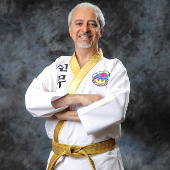 Man in a white martial arts uniform with a yellow belt against a dark background