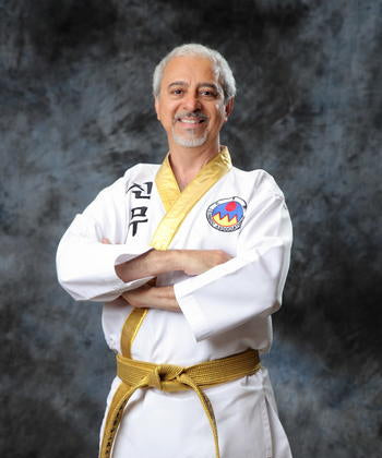 Man in a white martial arts uniform with a yellow belt against a dark background
