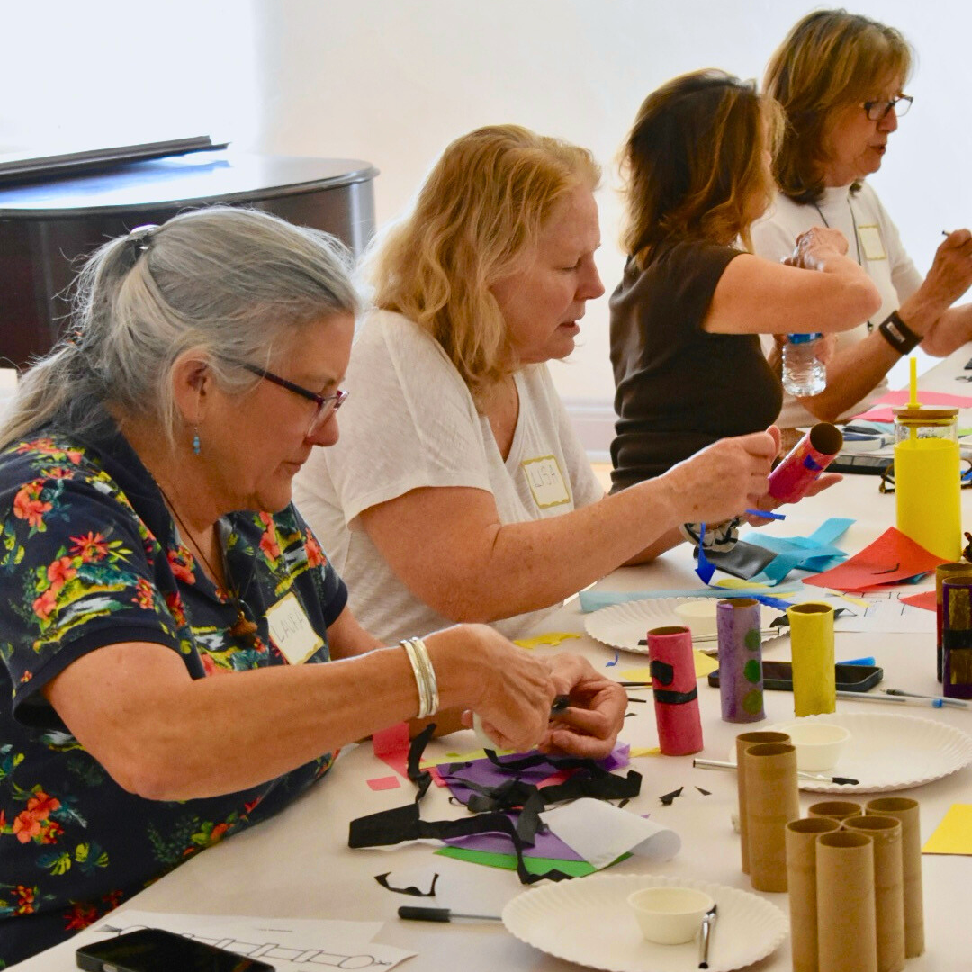 Group of women engaged in a craft activity at a table with various materials.