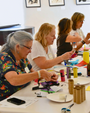 Group of women engaged in a craft activity at a table with various materials.