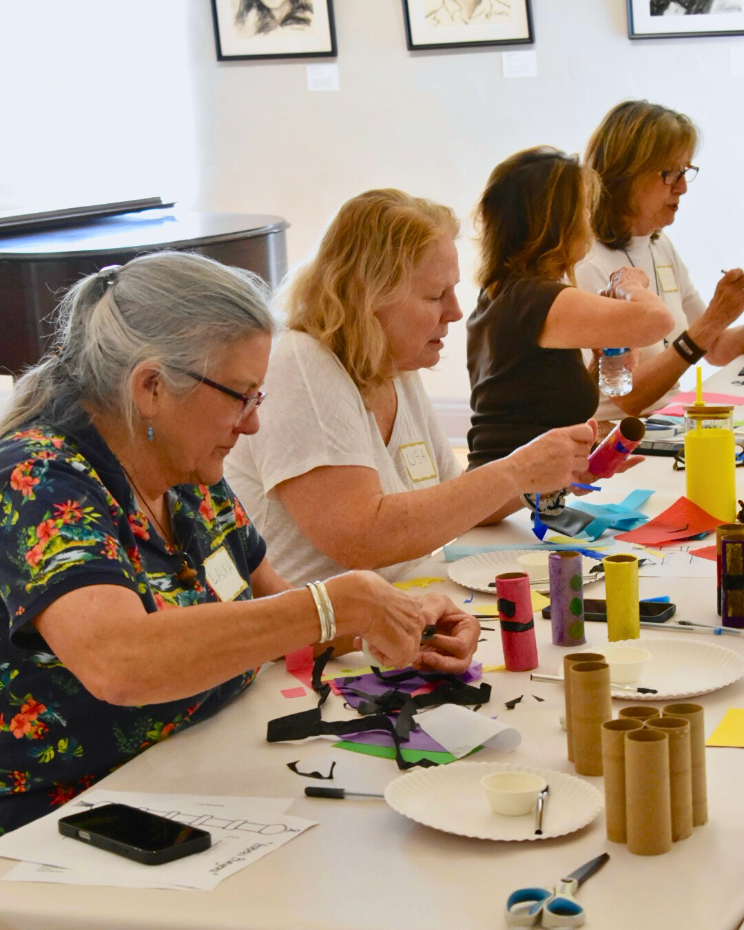 Group of women engaged in a craft activity at a table with various materials.