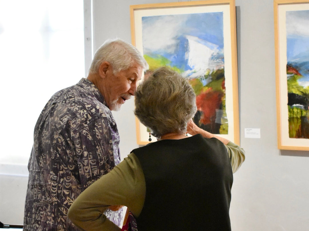 Two people looking at a painting in an art gallery.